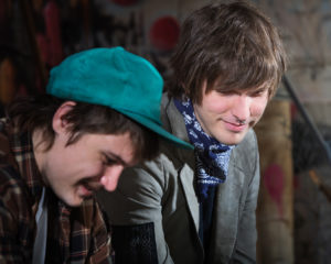Smiling teen friends sitting in urban scene outdoors